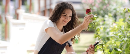 Teen girl florist with pruner cutting flowers